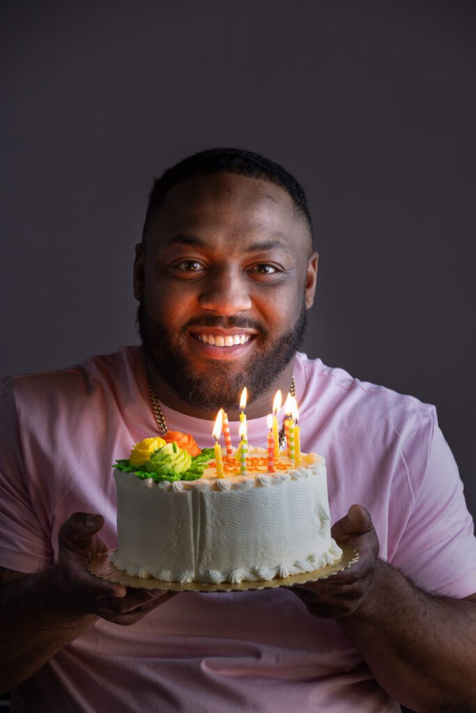 Leon Ford smiles as he holds a birthday cake with lighted candles